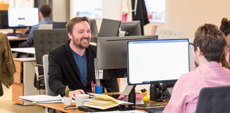 Muž sedící u stolu s kolegy, vyklízení kanceláří v Praze.